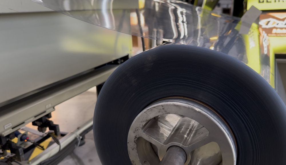 Roll of clear plastic sheet feeding thermoforming equipment at Stang Precision