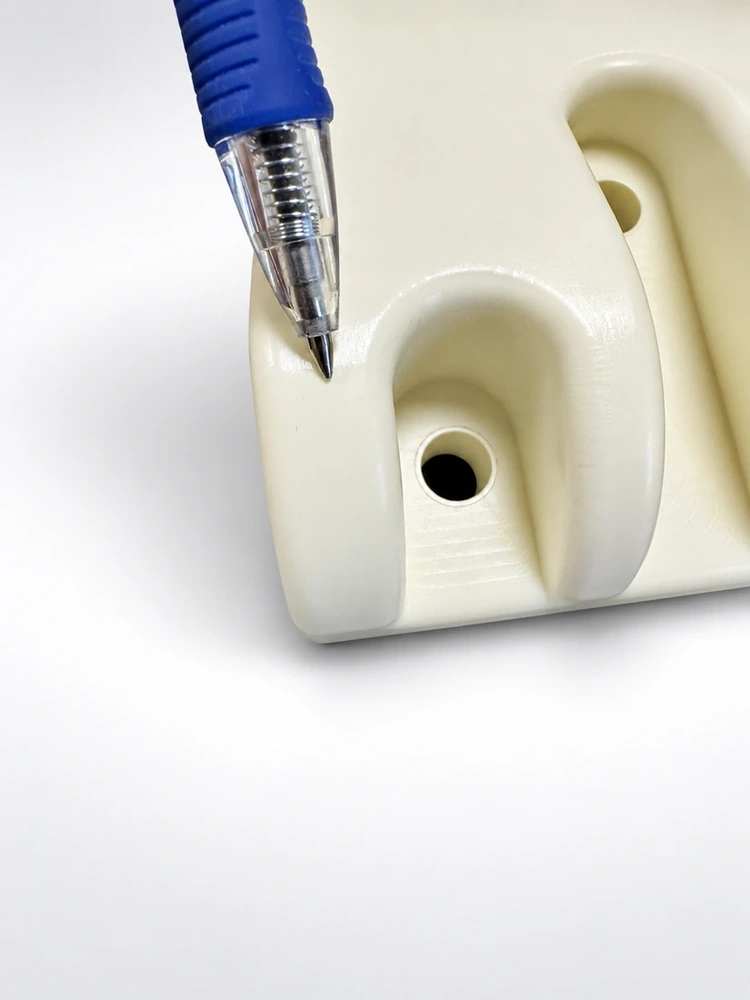 White thick-wall molded component with a blue pen showing the wall thickness