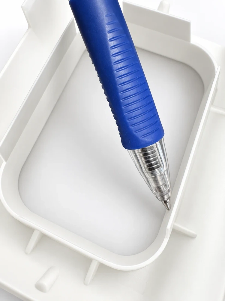 White thin-wall molded component beside a pen for scale