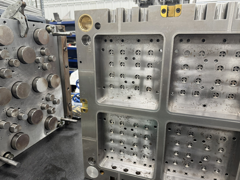 Open injection mold showing machined cavities and tooling components